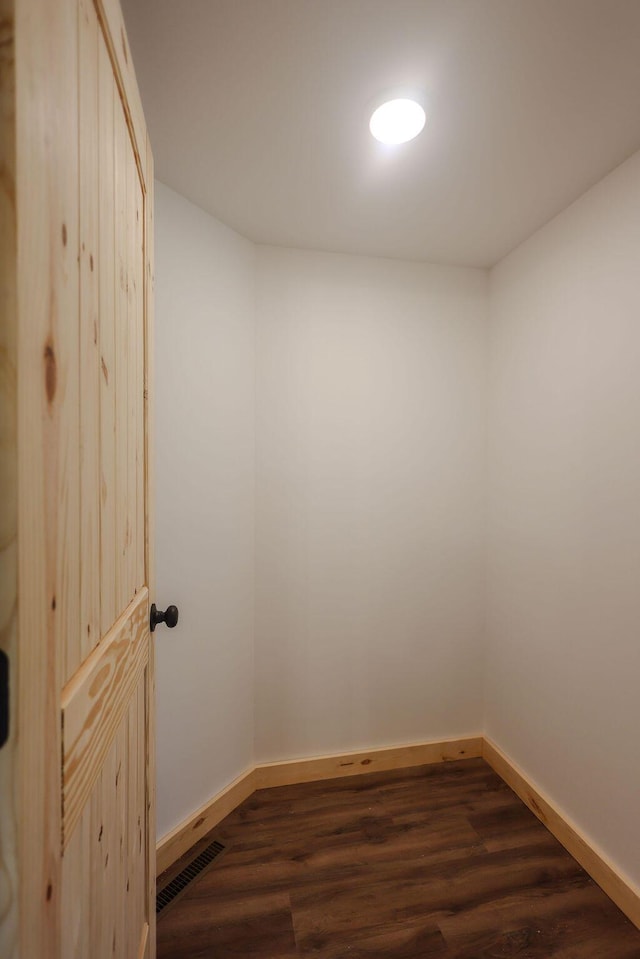 spare room featuring dark wood-type flooring, visible vents, and baseboards