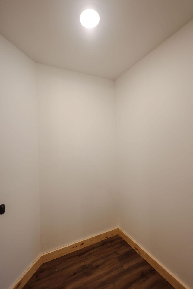 unfurnished room featuring baseboards and dark wood finished floors