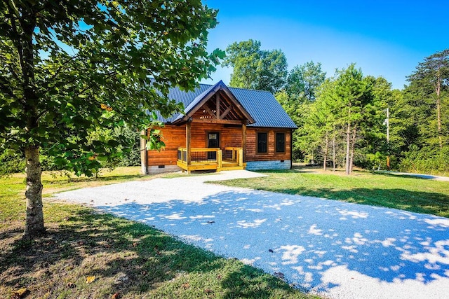 view of front facade with covered porch, crawl space, metal roof, driveway, and a front lawn