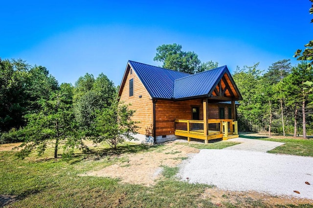 view of front facade with crawl space, covered porch, driveway, and metal roof