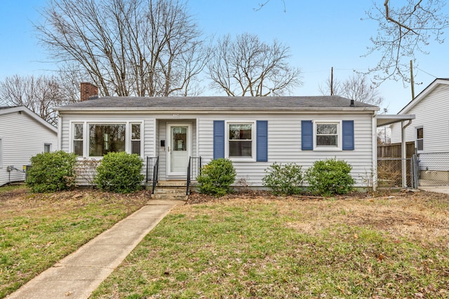 view of front of house featuring fence, a chimney, and a front lawn