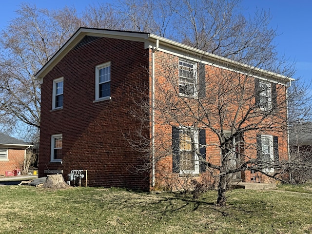 view of home's exterior featuring brick siding and a lawn