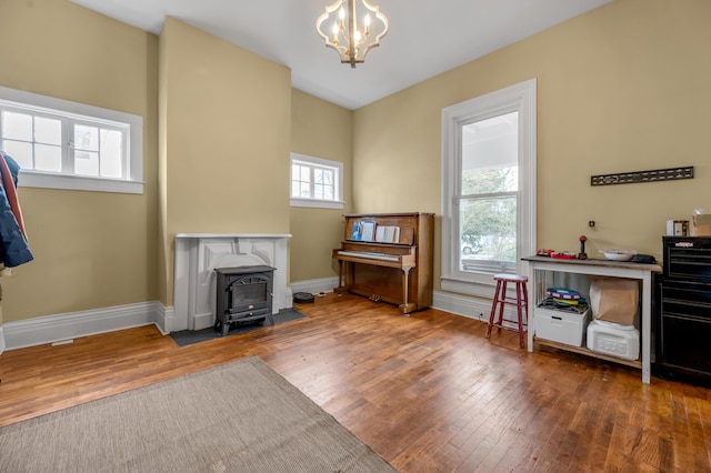 interior space with a chandelier, a wood stove, baseboards, and hardwood / wood-style floors