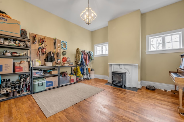 interior space with a wood stove, a notable chandelier, baseboards, and wood finished floors