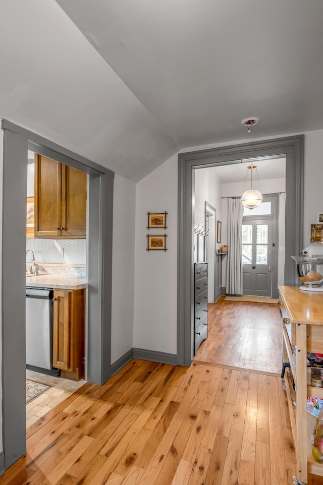 foyer entrance with lofted ceiling, baseboards, and light wood-style floors