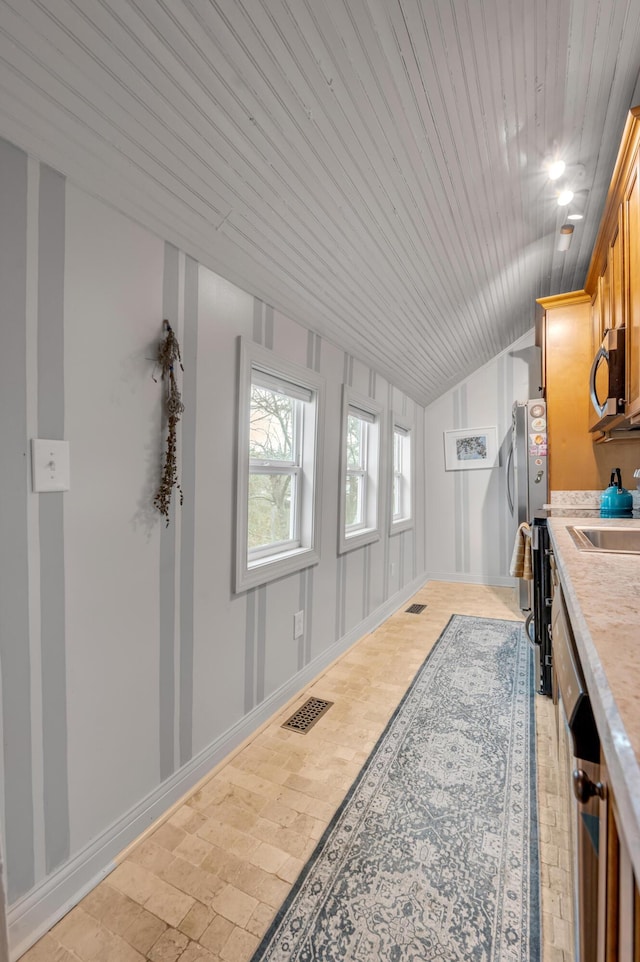 interior space featuring visible vents, baseboards, appliances with stainless steel finishes, vaulted ceiling, and light countertops