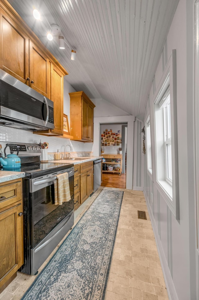 kitchen with a sink, visible vents, vaulted ceiling, light countertops, and appliances with stainless steel finishes