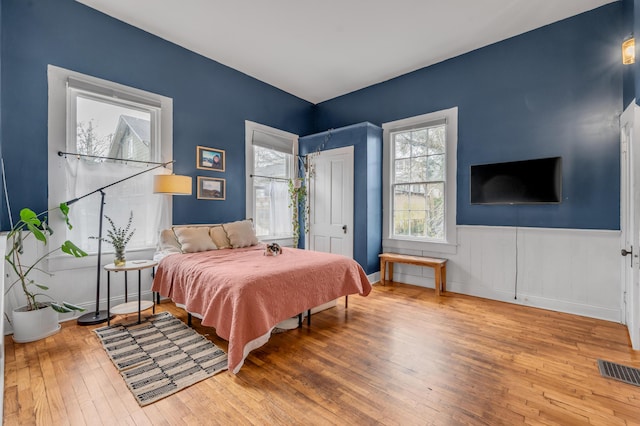 bedroom featuring a wainscoted wall, visible vents, and hardwood / wood-style floors