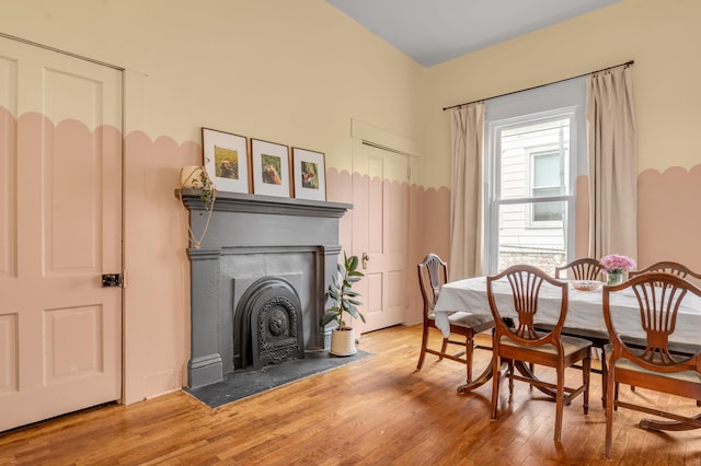 dining space featuring a fireplace with flush hearth and hardwood / wood-style floors