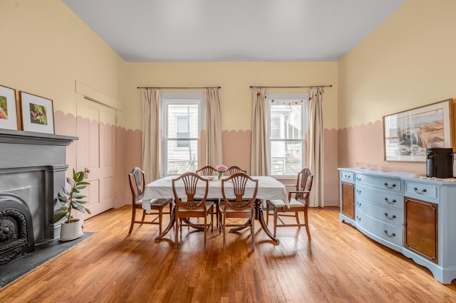 dining space with light wood-style floors and a fireplace