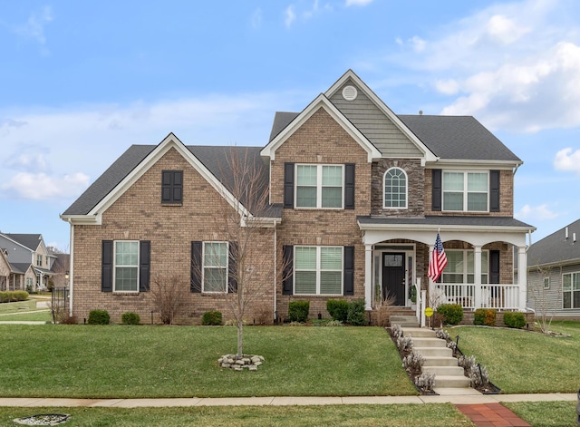 view of front of home with a porch, a front yard, and brick siding