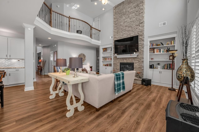 living area with a towering ceiling, a fireplace, visible vents, and wood finished floors