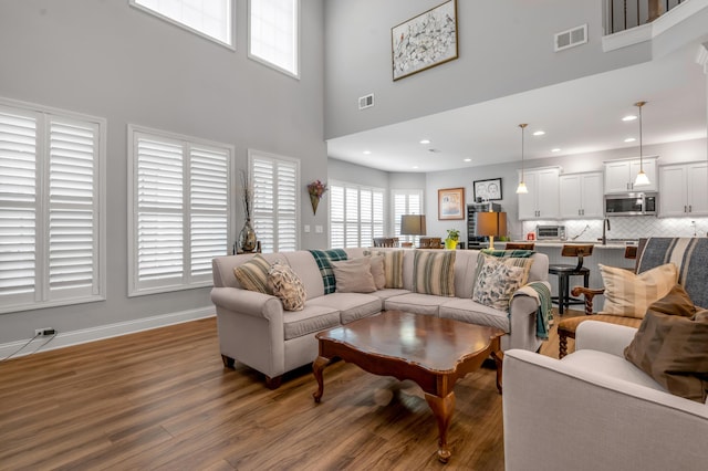 living room featuring baseboards, visible vents, wood finished floors, and recessed lighting