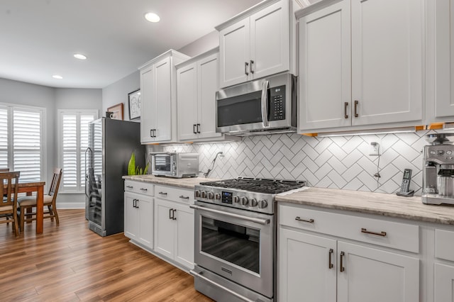 kitchen featuring a toaster, stainless steel appliances, recessed lighting, backsplash, and light wood-type flooring