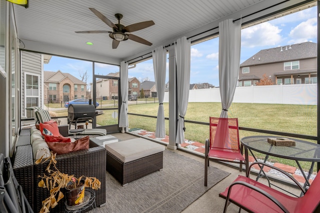 sunroom / solarium with a residential view and a ceiling fan