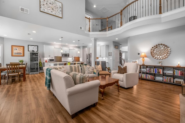 living room featuring decorative columns, stairs, visible vents, and wood finished floors