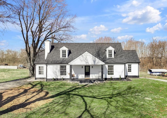 cape cod home featuring covered porch, a shingled roof, a chimney, and a front yard