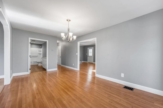 unfurnished dining area featuring light wood-type flooring, an inviting chandelier, visible vents, and baseboards