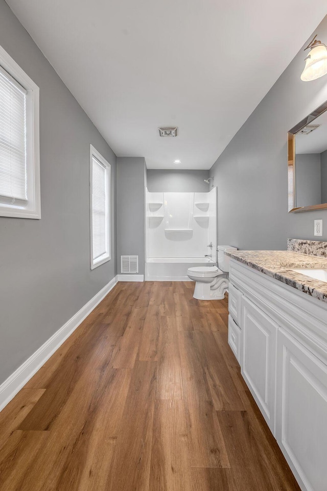 full bath featuring visible vents, vanity, baseboards, and wood finished floors