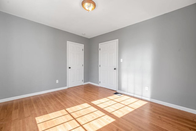 empty room featuring visible vents, baseboards, and wood finished floors