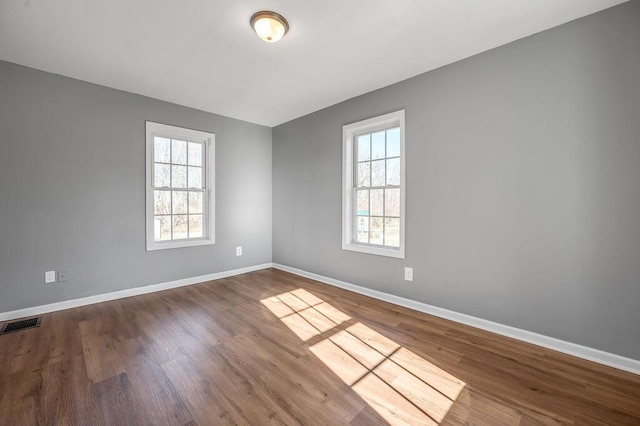 unfurnished room featuring plenty of natural light, baseboards, and wood finished floors