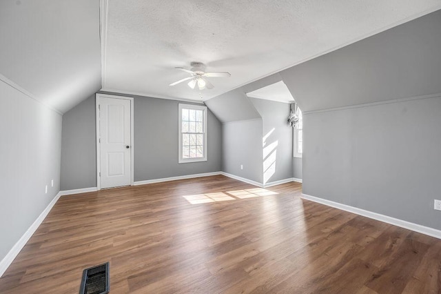 bonus room with lofted ceiling, visible vents, a textured ceiling, and wood finished floors