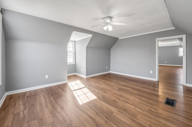 additional living space with vaulted ceiling, wood finished floors, visible vents, and baseboards