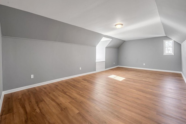 bonus room featuring light wood-style floors, lofted ceiling, and baseboards