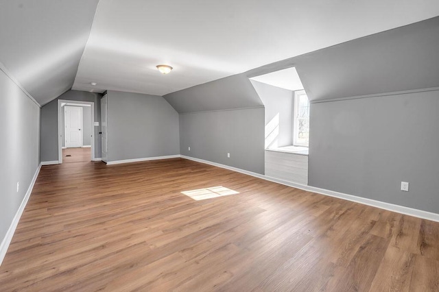 bonus room with lofted ceiling, baseboards, and wood finished floors