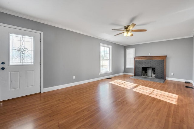 unfurnished living room with a brick fireplace, ornamental molding, and wood finished floors