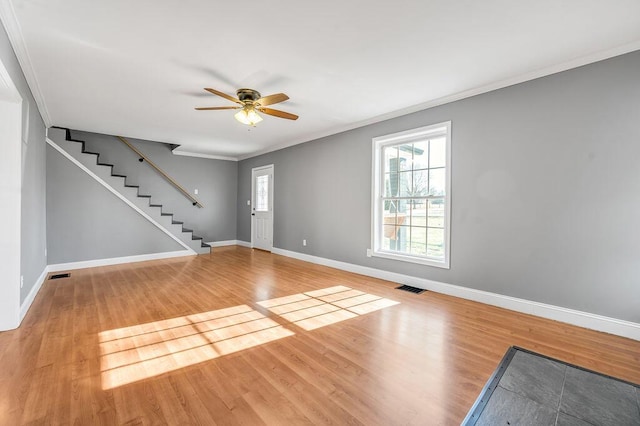 interior space featuring wood finished floors, visible vents, baseboards, stairs, and crown molding