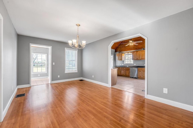 unfurnished living room featuring arched walkways, light wood finished floors, visible vents, baseboards, and ceiling fan with notable chandelier