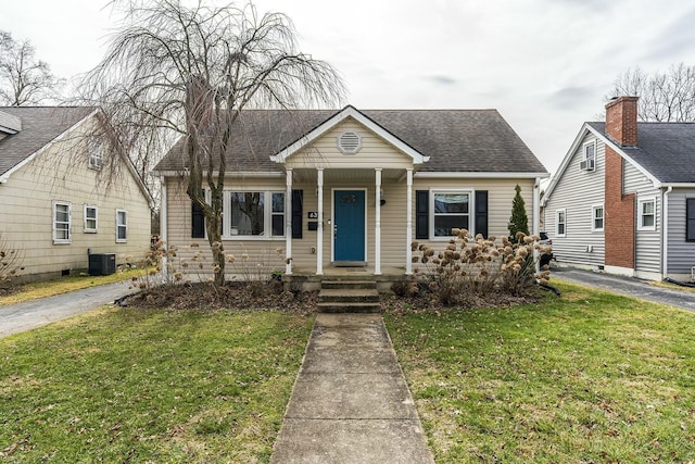 bungalow with a porch, cooling unit, roof with shingles, and a front yard