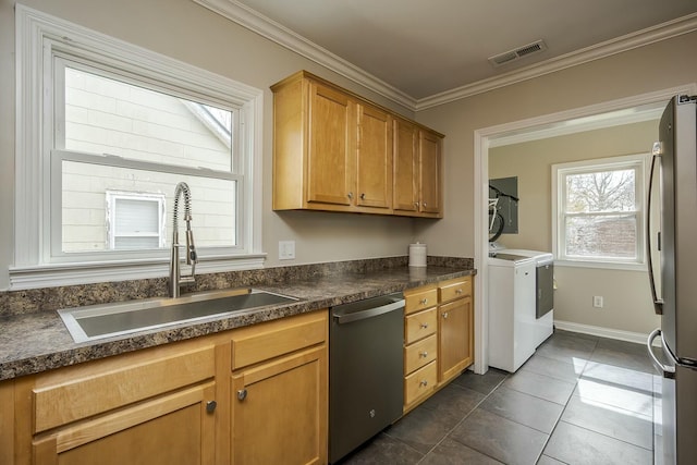 kitchen featuring crown molding, visible vents, appliances with stainless steel finishes, washing machine and dryer, and a sink