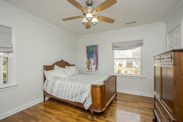 bedroom featuring crown molding, visible vents, baseboards, and hardwood / wood-style floors