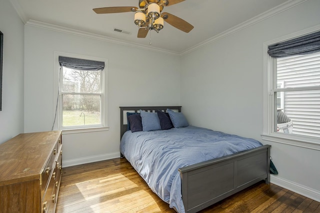 bedroom featuring baseboards, hardwood / wood-style flooring, visible vents, and crown molding