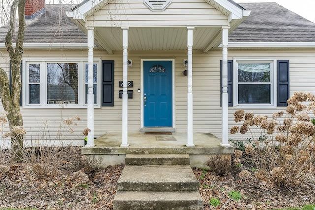 entrance to property featuring a shingled roof and a chimney