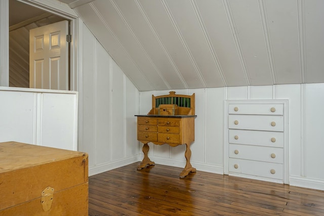 additional living space with vaulted ceiling, wood-type flooring, and a decorative wall