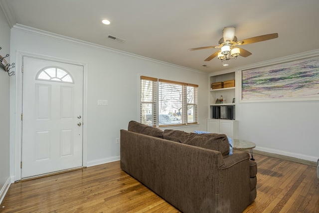 living area with hardwood / wood-style flooring, baseboards, visible vents, and crown molding