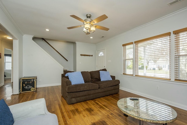 living room featuring wood finished floors, visible vents, baseboards, stairs, and ornamental molding