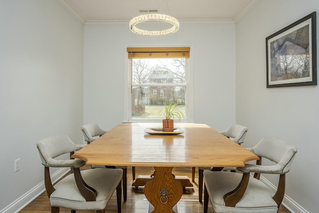 dining area featuring baseboards, visible vents, wood finished floors, and ornamental molding