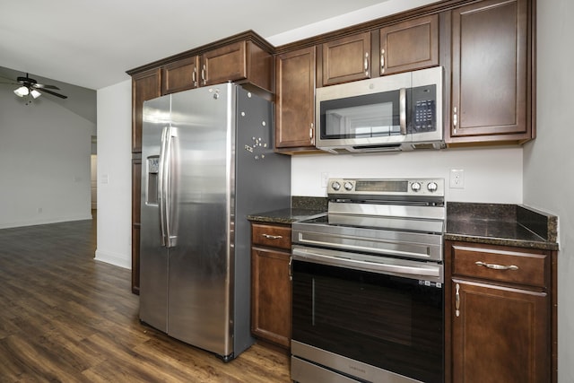 kitchen with dark wood-style floors, appliances with stainless steel finishes, a ceiling fan, dark brown cabinetry, and dark stone countertops