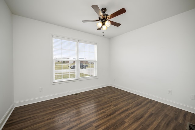 empty room with ceiling fan, dark wood finished floors, visible vents, and baseboards