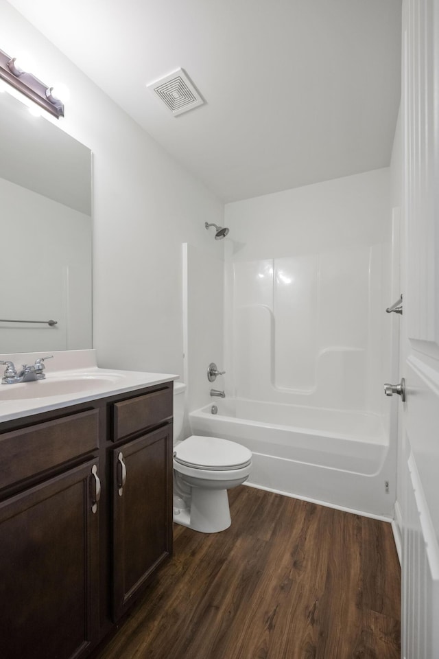 bathroom with shower / bath combination, visible vents, toilet, vanity, and wood finished floors