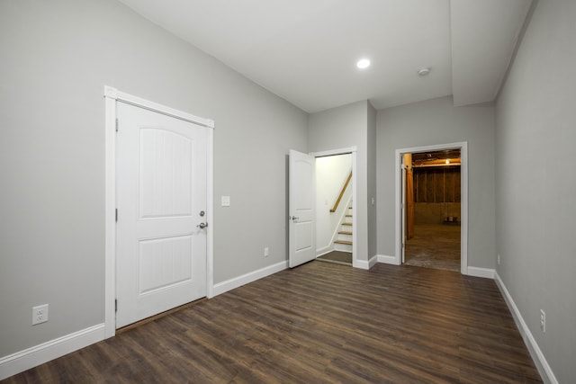 spare room with dark wood-type flooring, stairway, and baseboards