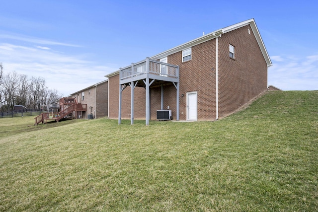 rear view of house featuring central AC, a yard, a deck, and brick siding