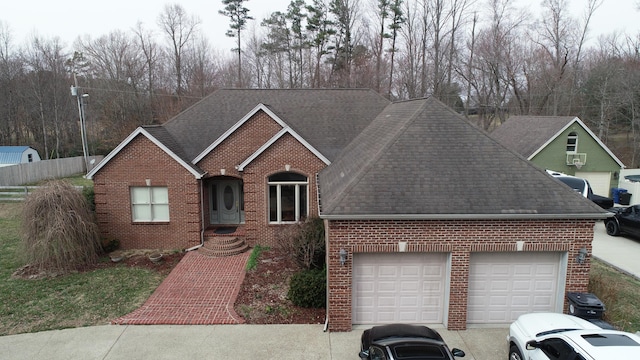 view of front of home with an attached garage, a shingled roof, concrete driveway, and brick siding