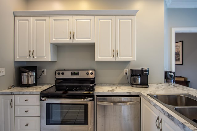 kitchen featuring appliances with stainless steel finishes, white cabinets, a sink, and ornamental molding