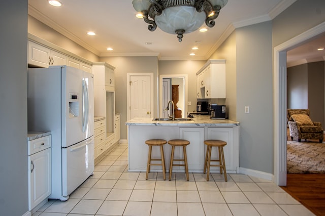 kitchen featuring a peninsula, a sink, white cabinetry, ornamental molding, and white fridge with ice dispenser