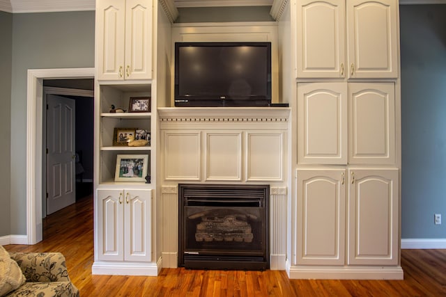 interior space with a fireplace, wood finished floors, white cabinets, and baseboards